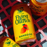 Three cans of Flying Ostrich Mango flavor drinks on a red grid background