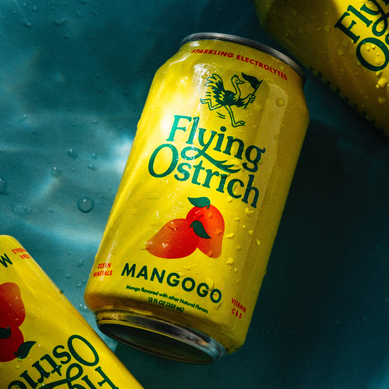 Three cans of Flying Ostrich Mango beer on a blue textured background